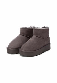Stivaletti alla caviglia in suede grigio con interni morbidi, punta arrotondata e suola piatta, caratterizzati da una superficie testurizzata e da un design minimalista.