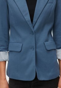 Blauw colbert met twee knopen, opgestikte zakken en opgerolde manchetten die een lichtblauwe en witte gestreepte voering laten zien. Gladde stoftextuur.