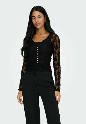 Sort blond lace top med lange ærmer og V-udskæring, med knaplukning foran med små hvide knapper og en cropped længde.