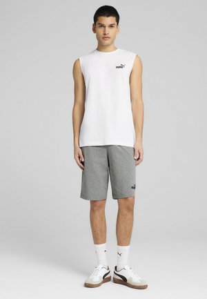 Hvid ærmeløs skjorte med sort Puma-logo, kombineret med grå shorts med Puma-logoet. Hvide sokker og sneakers fuldender outfittet.