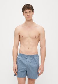 Modre karo bokserice z elastičnim pasom in enim gumbom za zapiranje. Lahka tkanina z gladko teksturo.