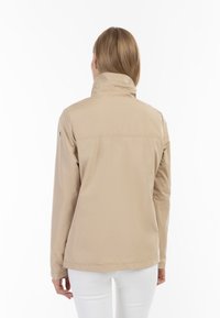 Beige kevyt takki, jossa on korkea kaulus, pehmeä pinta ja suora leikkaus. Ominaisuuksiin kuuluu sileä viimeistely ilman näkyviä metalliosia.