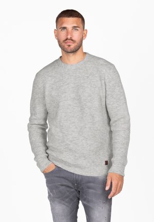 Grijze geribde trui van gebreid katoen, met een ronde halslijn en een klein bruin label. Draag het met versleten grijze spijkerbroek.