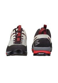 Un paio di scarpe sportive grigie, nere e rosse con lacci neri, linguette rosse e suole con il marchio Michelin, mostrate di fronte e di dietro.