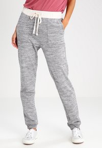 Grå sweatpants med en texturerad mönster, elastisk midja, snörning och sidofickor. Matchat med vita sneakers.