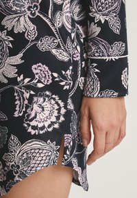Abito a stampa floreale in blu navy, con fiori rosa e bianchi. Maniche lunghe, dettagli con bottoni e uno spacco laterale per un tocco di stile.