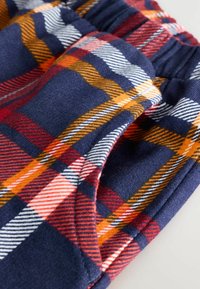 Pantaloni din flanel de culoare bleumarin, cu un model de carouri în nuanțe de roșu, portocaliu și alb, având o talie elastică și o textură moale.