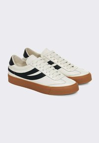 Sneakers in pelle bianca con strisce nere laterali, punta tonda, suola in gomma piatta e ruvida, e lacci testurizzati. Nome del marchio impresso sul lato esterno.