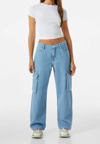 Ljust blå cargojaggers med lös passform, stora sidofickor, klassisk femficksdesign och subtilt urblekt denimtextur.