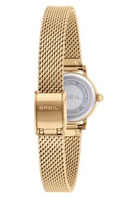 Montre en maille dorée avec un dos en acier inoxydable, présentant un cadran rond et une fermeture à clapet. Le bracelet a un design tissé et texturé.