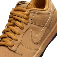 Tan lærersneaker med rund tå, teksturert mesh-tunge og flate lisser. Har en svart Nike-logo og subtile sømdetaljer.