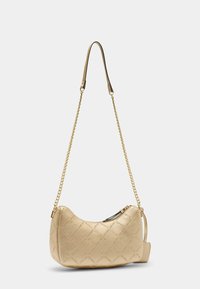 Borsa a spalla in pelle beige con una forma curvilinea, motivo a diamante testurizzato e una lunga tracolla a catena. Dotata di chiusura a zip superiore.