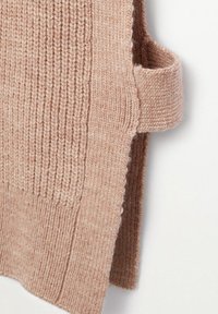 Stickad tröja i en mjuk beige nyans med ribbat mönster, med en sidoficka och rundad halsringning.