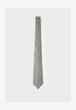 Cravate noire et blanche avec un motif géométrique en étoile et un petit emblème de lion doré près du bas.