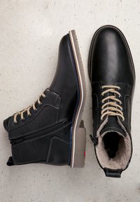 Schwarze Lederstiefel mit Schnürdesign, braunen Schnürsenkeln und Kunstfellfutter. Seitlicher Reißverschluss und strukturierte Gummisohle in kontrastierenden Farben.