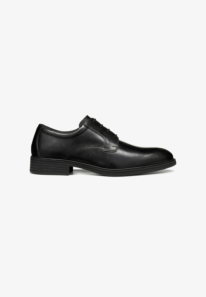 Chaussure habillée pour homme en cuir noir avec fermeture à lacets et petit talon empilé, vue de côté sur fond blanc.