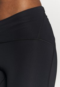 Svarta högmidjade leggings gjorda av elastisk, slät tyg. Har förstärkta sömmar och en elegant design med en matt yta.