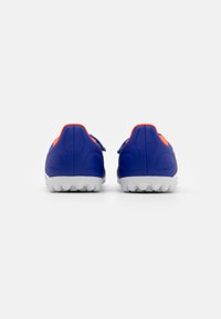 Zapatillas deportivas azules con acentos naranjas, material sintético texturizado y una suela blanca con pequeños tacos antideslizantes. Sin marcas visibles.