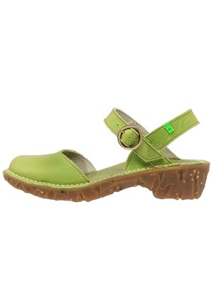 Sandale ouverte en cuir vert avec bride de cheville réglable, boucle ronde en bronze et semelle en caoutchouc marron texturée avec petit talon.