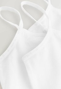 Witte katoenen camisoles met verstelbare bandjes en kantdetails, met een gladde textuur en een minimalistisch mouwloos ontwerp.