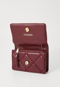 Burgundy leather wallet with quilted texture, gold logo and hardware, a snap closure, and zippered pocket inside.