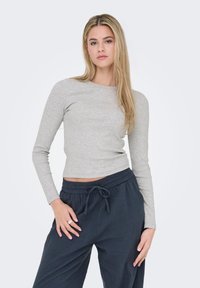 Γκρι μπλούζα μακρυμάνικη από απαλό ύφασμα, με στρογγυλή λαιμόκοψη και εφαρμοστή γραμμή. Συνδυάζεται με σκούρα, φαρδιά παντελόνια με κορδόνι στη μέση.