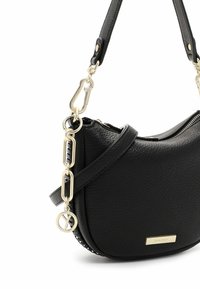 Sac à épaule en cuir noir texturé avec chaîne dorée, fermoir et plaque logo, avec un fond arrondi et une fermeture éclair.
