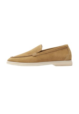 Scarpa slip-on in suede marrone con punta arrotondata, suola beige a profilo basso e dettagli di cucitura minimi lungo la parte superiore.