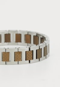 Bracelet en métal composé de maillons rectangulaires en argent alternant avec des maillons rectangulaires bruns texturés, avec une finition lisse et polie et un design moderne.