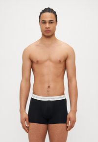 Caleçons de boxeur noirs avec une taille grise portant l'inscription "Copenhagen Studios". Tissu doux et design ajusté, sans motifs ni accents visibles.