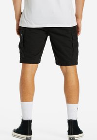 Sorte cargo shorts med sidelommer, lavet af et holdbart stof; iført med hvide sokker og sorte høj-top sneakers.
