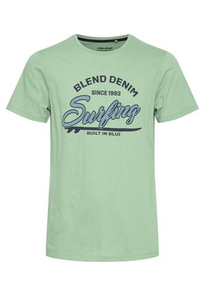 Light green cotton t-shirt featuring a round neck and short sleeves. Text graphic in dark blue and black: "BLEND DENIM Surfing BUILT IN BLUE."