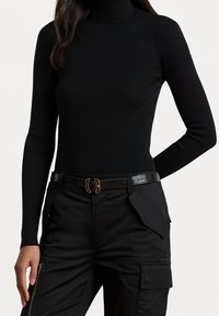 Černý žebrovaný rolák s dlouhými rukávy, doplněný o černé kalhoty s cargo kapsami a texturovaným pásem se zlatou sponou.