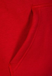 Tessuto di felpa rossa con tasca frontale, texture morbida e dettagli di cucitura liscia lungo i bordi.