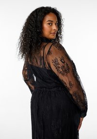Black lace dress featuring long sheer sleeves, floral patterns, a cinched waist, and a smooth fabric texture, with a collar and button detail.
