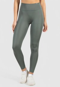 Högmidjade, figurnära leggings i olivgrönt, tillverkade av ett mjukt och stretchigt material med minimala sömmar och en subtil glans.