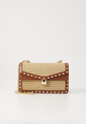 Rectangular woven beige handbag with brown leather trim, gold pyramid studs, square gold clasp, and gold chain strap, on white background.