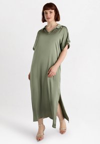 Lång grön klänning med krage, korta uppvikta ärmar och sidoflikar. Tillverkad av mjukt, lätt tyg med en avslappnad passform.