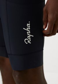 Shorts de cyclisme de couleur marine en tissu extensible et lisse. Présentent le logo blanc "Rapha." sur la cuisse et des accentuations de couture contrastantes.