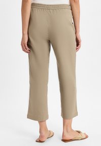 Lichte, khaki cropped broeken met een elastische tailleband, voorzien van een soepele textuur en een nette zoom. Gepaarde met beige instapsandalen.