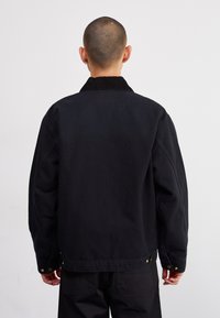 Musthave musta kanvasjakk, millel on sametkaelus, pikad varrukad ja nööpidega mansetid. Omab mugavat lõiget ja sileda tekstuuri.