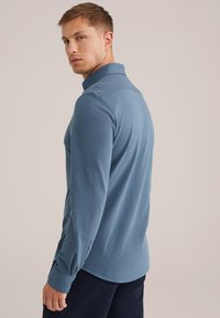 Garās piedurknes polo krekls bālgani zilos audumos. Tam ir klasiskā apkakle, pogu detaļa un pieguļošs dizains. Mīksta tekstūra ar smalku stiepšanos.