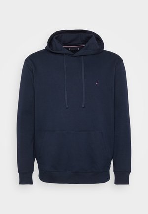 Marineblaue Kapuzenjacke aus Baumwolle, mit einer vorderen Tasche, Kordeln und einem kleinen Logo mit roten und weißen Akzenten auf der Brust.