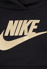 Fekete szövet pulóver, nagy arany "NIKE" logóval és szárnnyal, puha tapintású és standard kapucnival.
