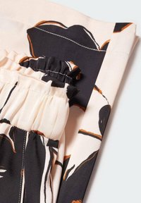Tissu floral avec un fond crème, présentant des motifs noirs et oranges ; comprend une taille froncée et des bords lisses. Matériau doux et léger.