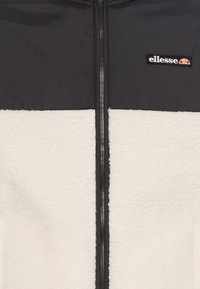 Fleecejacka med en färgblockdesign i svart och kräm. Har en dragkedja framtill och en ellesse-logotyp på den övre vänstra sidan. Mjuk textur.