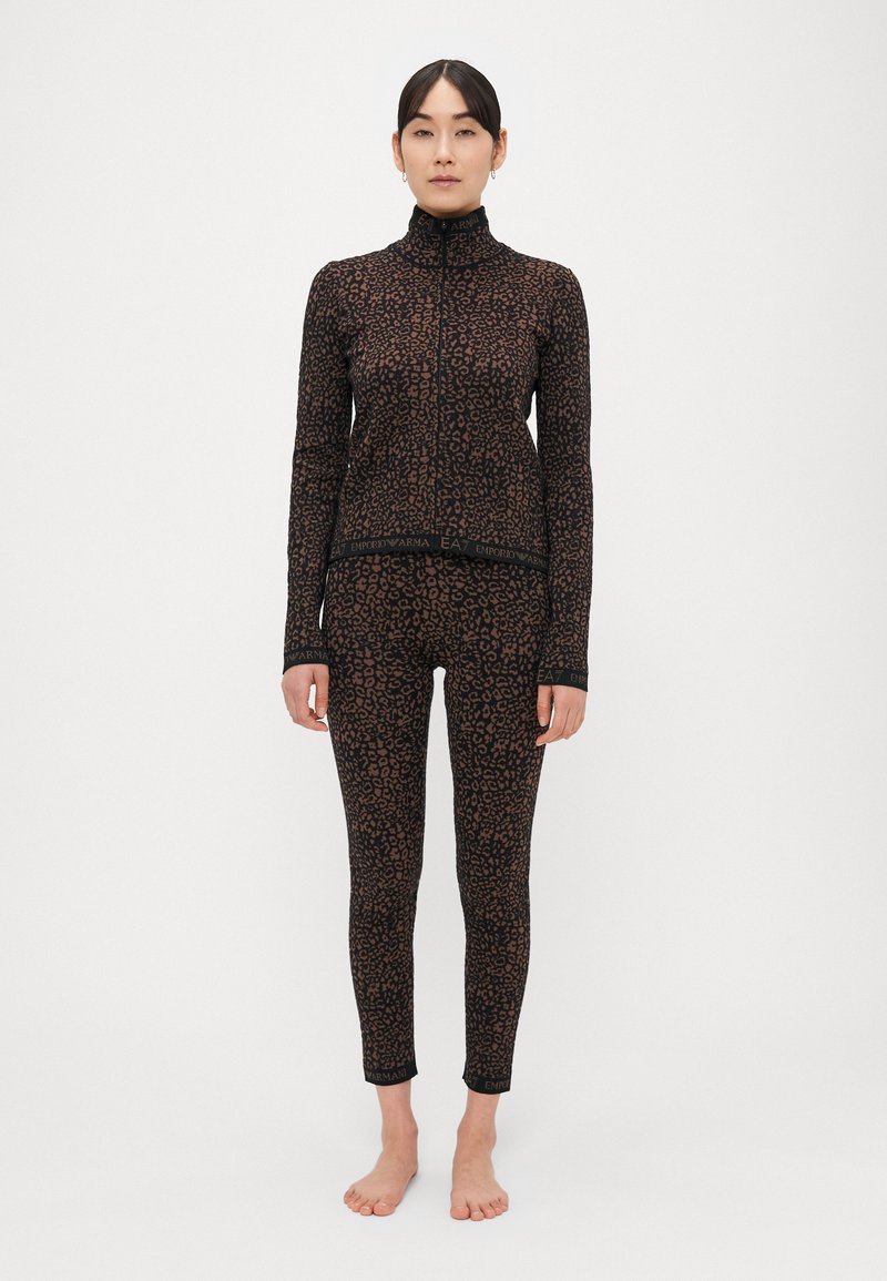 Čierny a hnedý leopardí vzor športového oblečenia, ktorý zahŕňa dlhý top na zips s dlhým rukávom a priliehavé legíny s logovanými detailmi na lemoch.