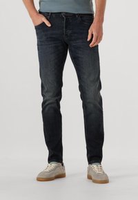 Donker gewassen denim jeans met een slim fit, voorzien van vijf zakken en subtiele vervaging. Draag ze met lichtgrijze sneakers met een gumzool.