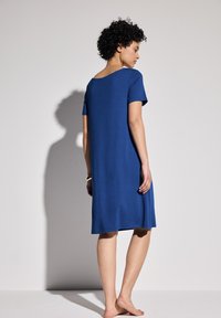 Niebieska sukienka z krótkim rękawem, wykonana z gładkiego materiału, o długości do kolan i luźnym kroju, z szerokim dekoltem i prostym wzornictwem.