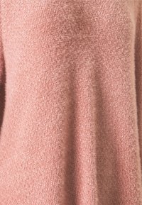 Maglione rosa lavorato a maglia con una finitura texturizzata e pelosa. Caratterizzato da una vestibilità ampia e maniche lunghe. Il materiale appare morbido e accogliente.